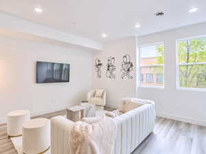 Living area with light wood finished floors, baseboards, visible vents, and recessed lighting