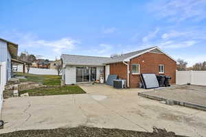 Back of house with brick siding, a patio, roof with shingles, cooling unit, and a fenced backyard