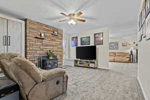 Carpeted living area featuring a wood stove, baseboards, a ceiling fan, and a textured ceiling