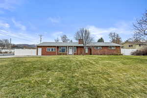 Ranch-style house with fence, a front lawn, and brick siding