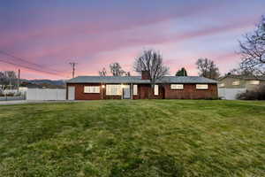 View of front of house featuring brick siding, a front yard, and fence