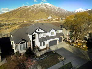 View of front of home with driveway, stucco siding, a mountain view, and roof with shingles