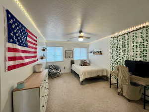 Southeast Bedroom featuring light carpet, a textured ceiling, and a ceiling fan