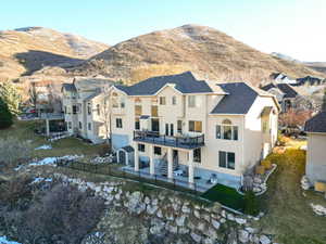 Exterior space featuring a patio, stucco siding, a shingled roof, a deck with mountain view, and a fenced backyard