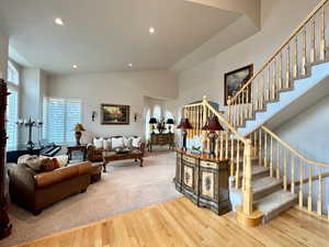 Living room with stairs, high vaulted ceiling, wood finished floors, and recessed lighting