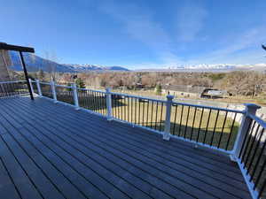 Deck with a fenced backyard, a mountain view, and a yard