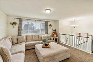 Living room with a chandelier, a textured ceiling, and carpet flooring