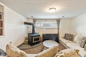 Living area with a textured ceiling, carpet floors, and a wood stove