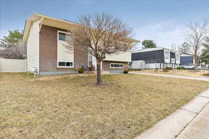 View of front facade with brick siding, a front yard, and fence