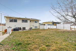 Rear view of property with a yard and fence