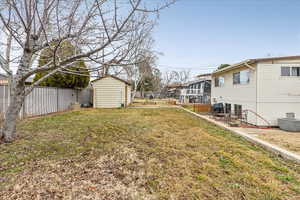 View of yard with a storage shed, a fenced backyard, a residential view, and an outbuilding