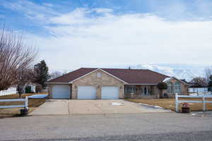 Single story home featuring brick siding, a shingled roof, an attached garage, fence, and driveway