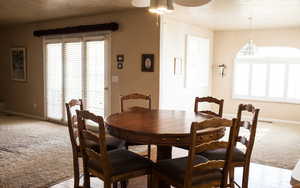 Dining space featuring a ceiling fan, light carpet, a textured ceiling, and baseboards