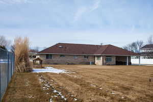 Back of house featuring central AC, fence, a lawn, and brick siding