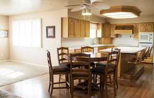 Dining space featuring a ceiling fan, a textured ceiling, baseboards, and dark wood-style flooring