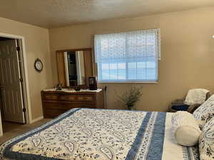 Carpeted bedroom featuring a textured ceiling and baseboards