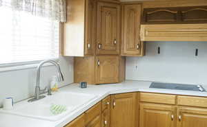 Kitchen with brown cabinets, electric stovetop, light countertops, and a sink