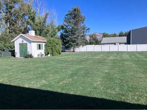 View of yard featuring an outbuilding, fence, and a mountain view