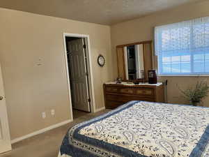 Bedroom featuring a textured ceiling, carpet, and baseboards