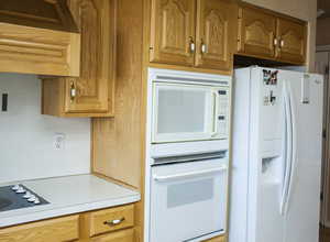 Kitchen featuring light countertops, white appliances, and brown cabinets