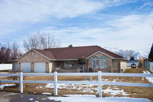 View of front of property with a garage, brick siding, and a fenced front yard