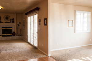 Unfurnished living room featuring a high end fireplace, plenty of natural light, a textured ceiling, and baseboards