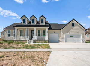 View of front facade with a porch, concrete driveway, an attached garage, and roof with shingles