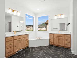 Bathroom featuring two vanities and a bath