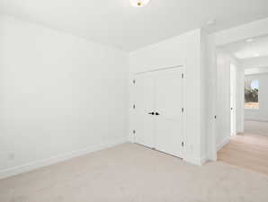 Unfurnished bedroom with light colored carpet and a closet