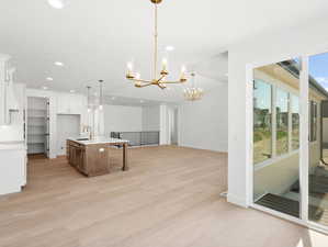 Kitchen with a chandelier, recessed lighting, light countertops, white cabinetry, and light wood-style flooring