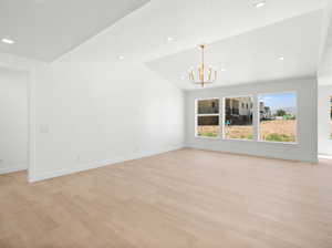 Empty room featuring a chandelier, light wood finished floors, and recessed lighting