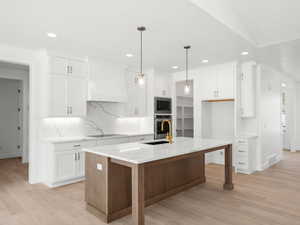Kitchen featuring appliances with stainless steel finishes, custom range hood, recessed lighting, backsplash, and white cabinets