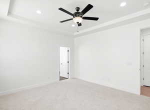 Empty room with recessed lighting, a smoke detector, light carpet, ceiling fan, and a raised ceiling