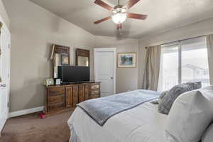 Carpeted bedroom with a ceiling fan, a textured ceiling, and baseboards