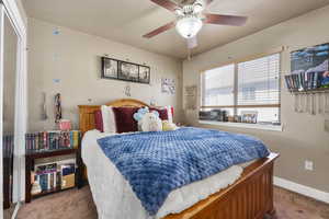 Carpeted bedroom with a textured ceiling, ceiling fan, and baseboards