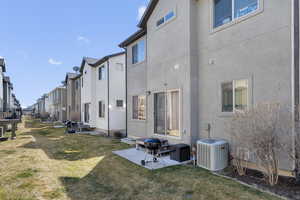 Back of house with a patio, a yard, stucco siding, and central air condition unit