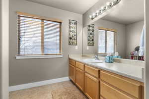 Bathroom featuring baseboards, a textured ceiling, vanity, and tile patterned floors