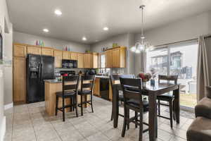 Kitchen with a kitchen island, a notable chandelier, black appliances, and light tile patterned floors