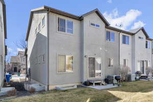 Rear view of property with a patio, a lawn, cooling unit, and stucco siding