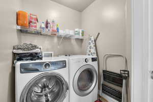 Washroom featuring a textured ceiling, laundry area, and washing machine and clothes dryer