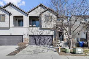 Townhome / multi-family property with a garage, driveway, a balcony, and stucco siding