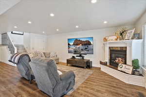 Living area featuring a fireplace, recessed lighting, visible vents, stairway, and wood finished floors