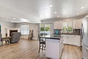 Kitchen with a breakfast bar, a fireplace, a kitchen island, a sink, and freestanding refrigerator