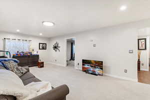 Carpeted living area with baseboards and recessed lighting