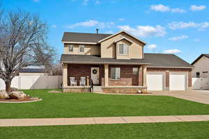 Traditional home featuring concrete driveway, an attached garage, covered porch, fence, and brick siding