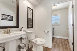 Bathroom featuring toilet, wood finished floors, visible vents, and baseboards