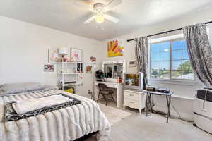 Bedroom featuring a ceiling fan, carpet, and a textured ceiling