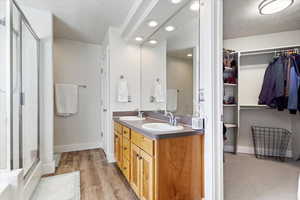 Full bath featuring double vanity, a stall shower, a spacious closet, and a sink