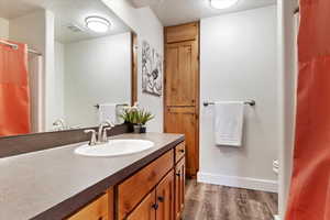 Bathroom with baseboards, visible vents, toilet, wood finished floors, and vanity