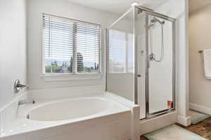 Bathroom with a garden tub, a shower stall, and wood finished floors